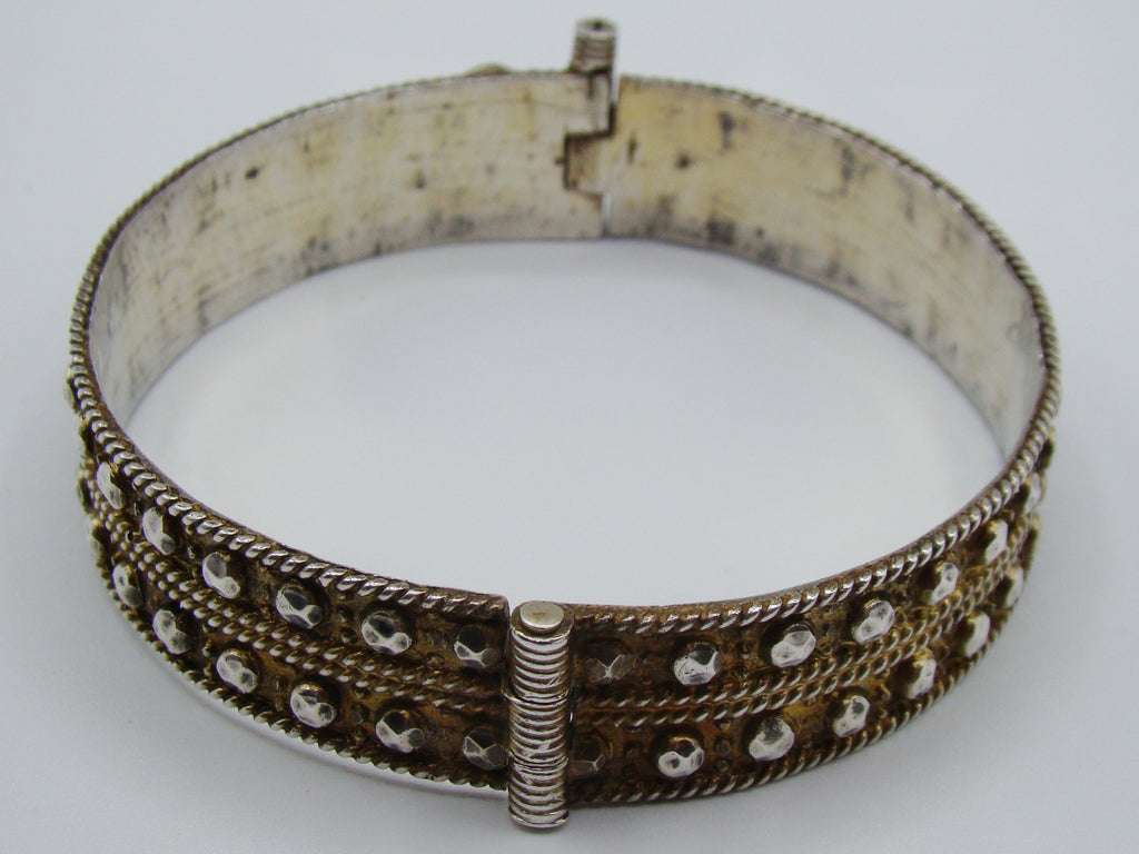 Side view of the silver bangle showing raised faceted metal accents and discolouration inside.