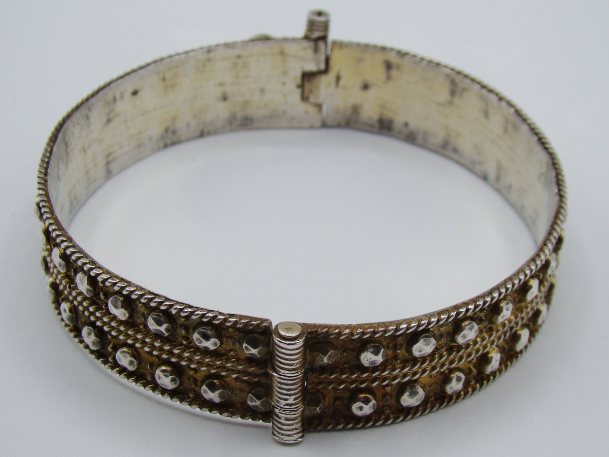 Side view of the silver bangle showing raised faceted metal accents and discolouration inside.