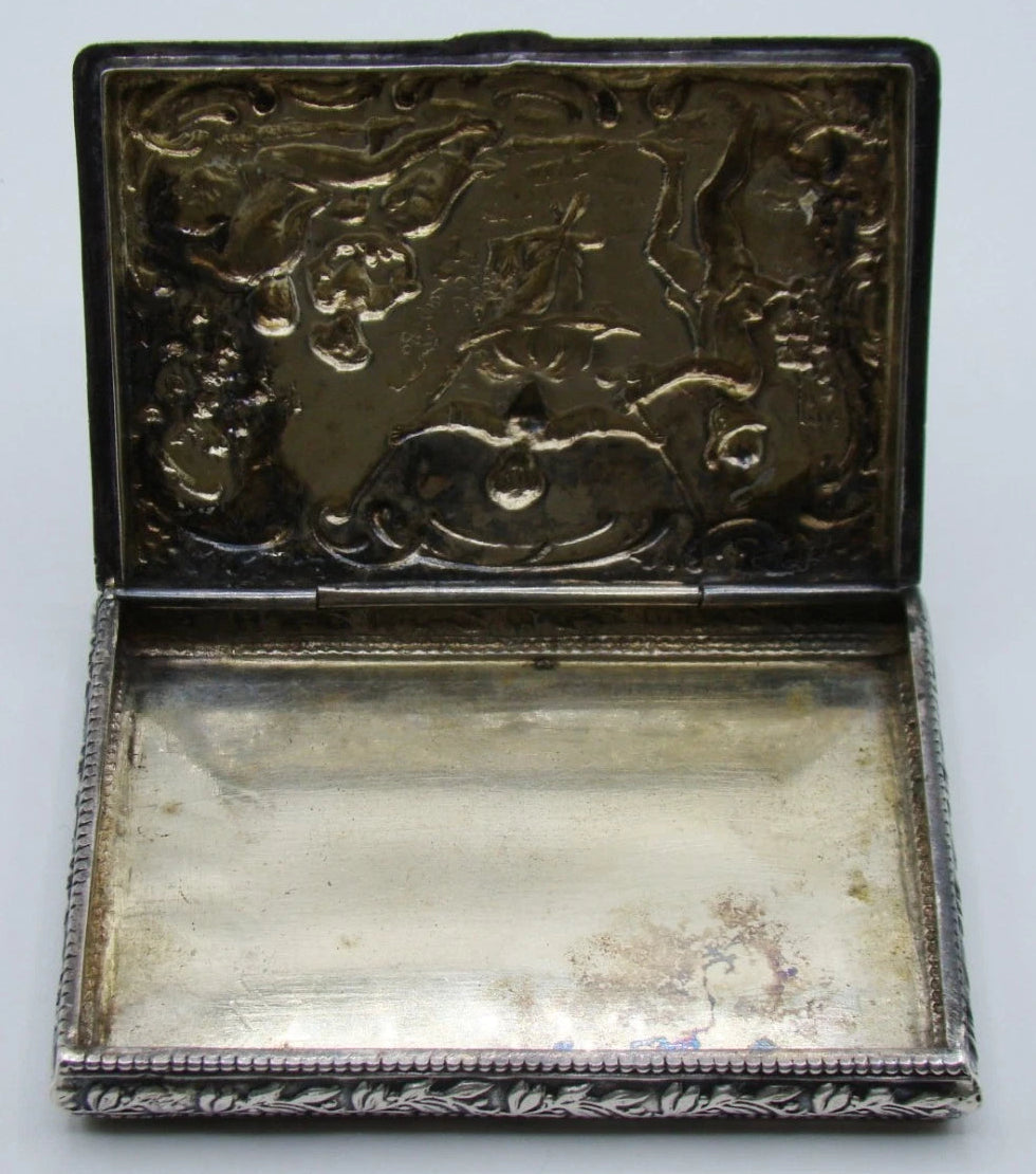 Open silver box showing its plain interior and the reverse of the relief-decorated lid.