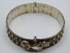 Opposite side of the silver bangle showing rope-like borders and darkened decorative recesses.