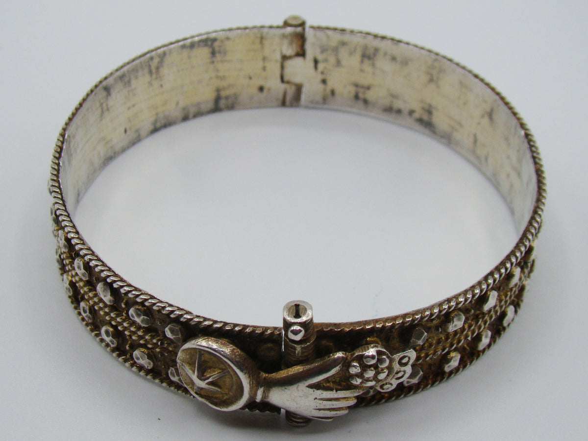 Opposite side of the silver bangle showing rope-like borders and darkened decorative recesses.
