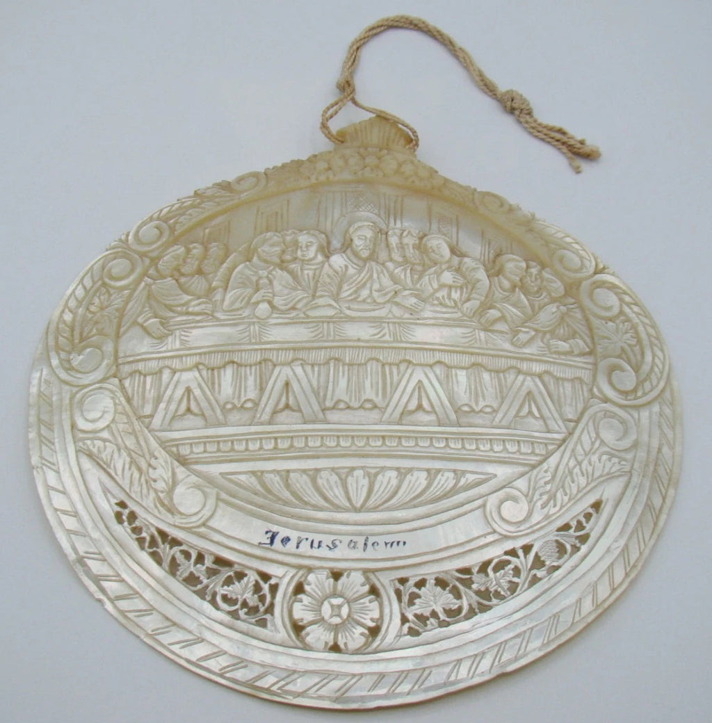 Angled view of carved Last Supper shell showing Christ and apostles within a scrolling floral border