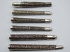 Front view of six silver filigree mouthpieces with varied scrollwork and ornamental collars
