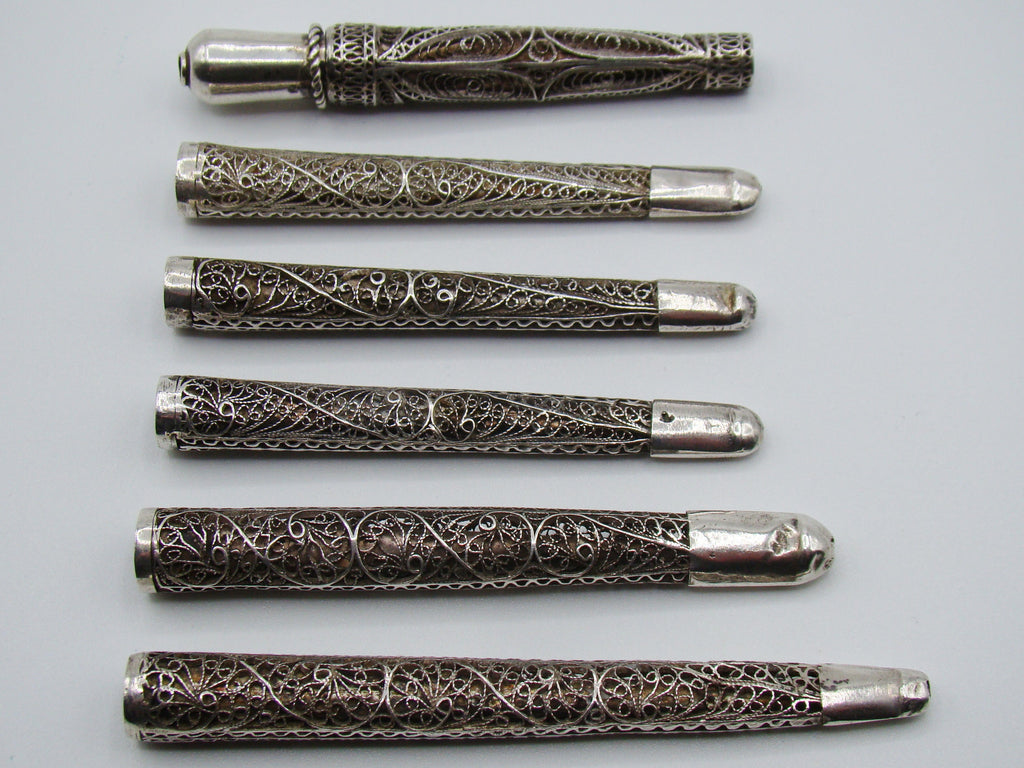 Front view of six silver filigree mouthpieces with varied scrollwork and ornamental collars