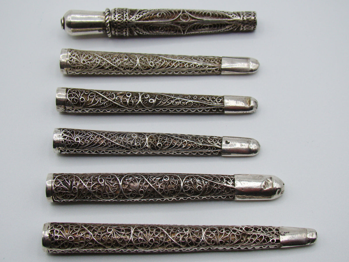 Front view of six silver filigree mouthpieces with varied scrollwork and ornamental collars