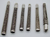 Six antique silver mouthpieces arranged horizontally, showing their different lengths and filigree patterns