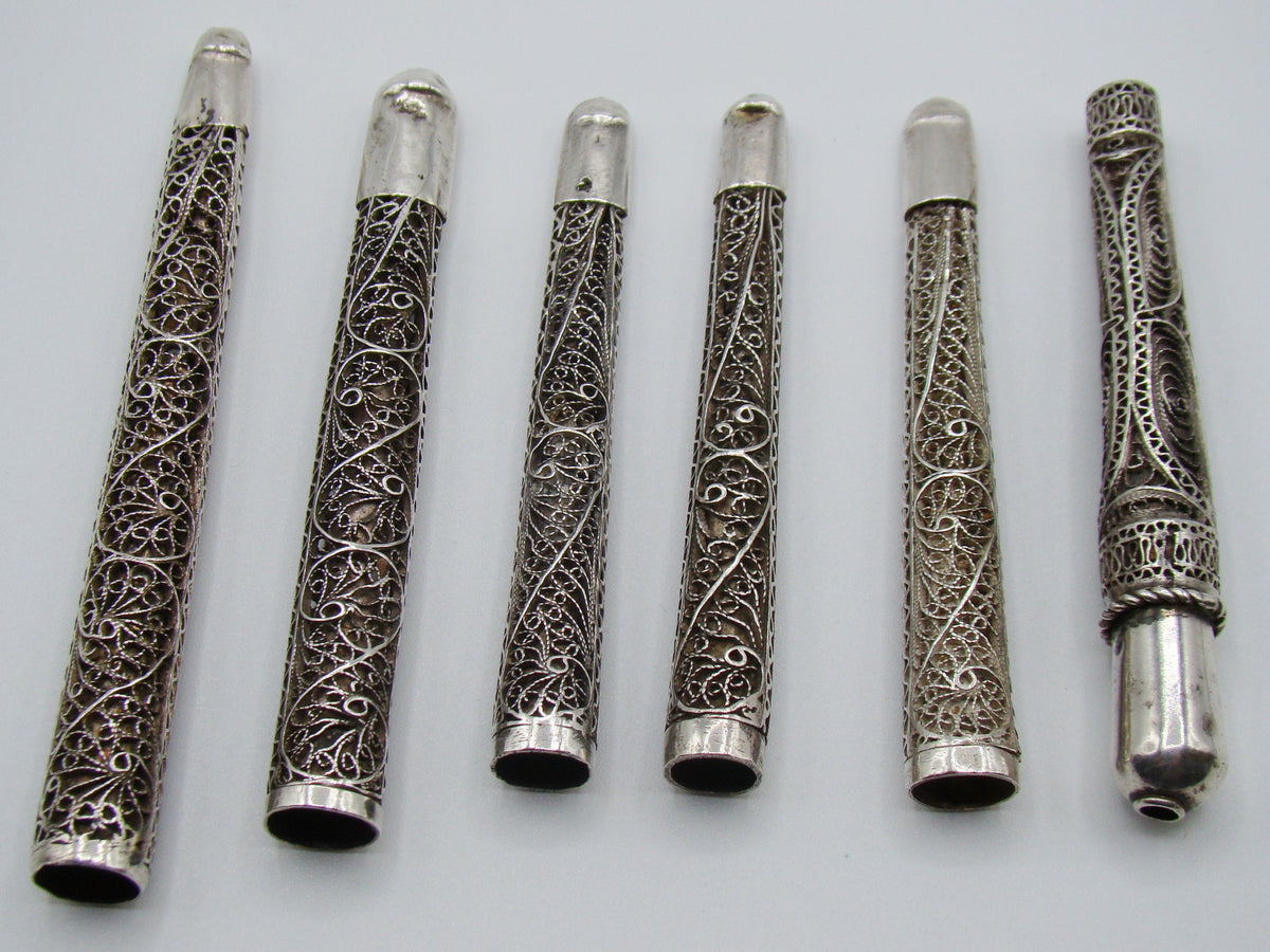 Six antique silver mouthpieces arranged horizontally, showing their different lengths and filigree patterns
