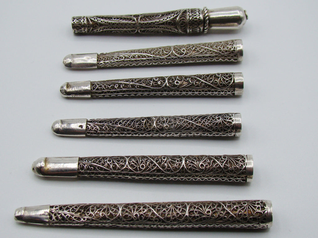 Reverse view of six silver filigree mouthpieces with open tubular ends visible