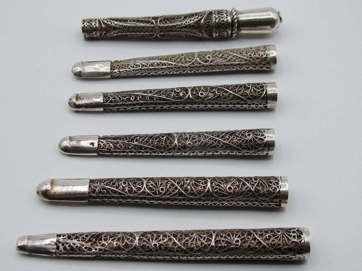 Reverse view of six silver filigree mouthpieces with open tubular ends visible
