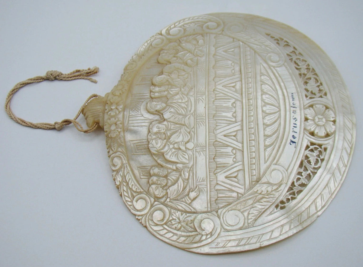 Inverted full view of Last Supper shell showing relief carving and attached frayed cord