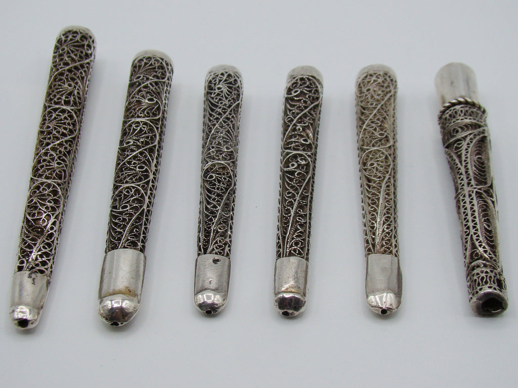 Angled view of the open ends and intricate filigree on six antique silver mouthpieces