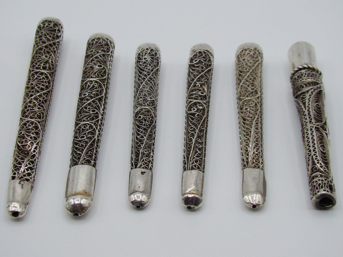 Angled view of the open ends and intricate filigree on six antique silver mouthpieces