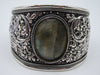 Side view of silver cuff showing scrolling foliage, flowers and pierced decoration