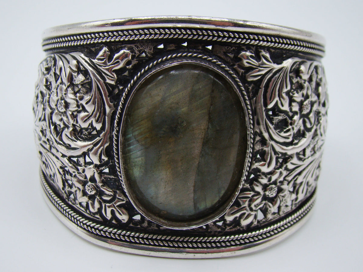 Side view of silver cuff showing scrolling foliage, flowers and pierced decoration
