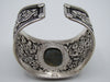 Opposite side of silver cuff with detailed floral and leaf scrollwork between rope-like borders