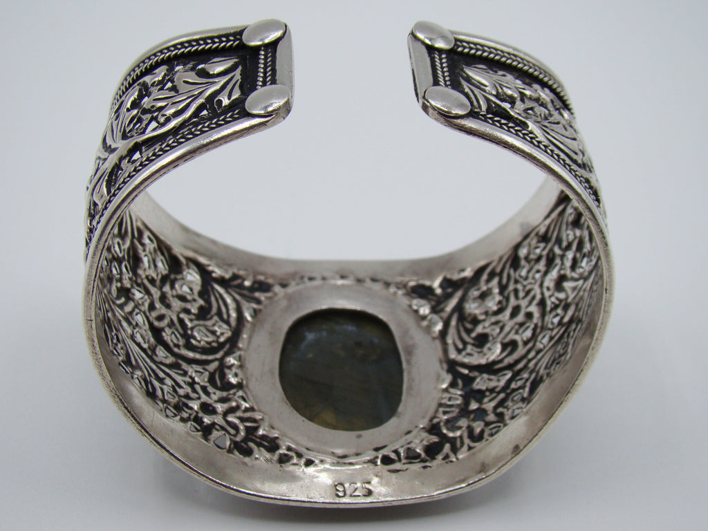Opposite side of silver cuff with detailed floral and leaf scrollwork between rope-like borders