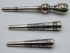 Reverse view of three engraved antique silver mouthpieces with gold-coloured details