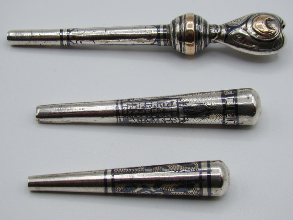 Reverse view of three engraved antique silver mouthpieces with gold-coloured details