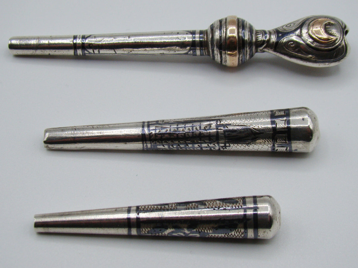 Reverse view of three engraved antique silver mouthpieces with gold-coloured details