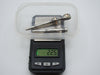 Three antique silver mouthpieces on a scale displaying 22.5 grams