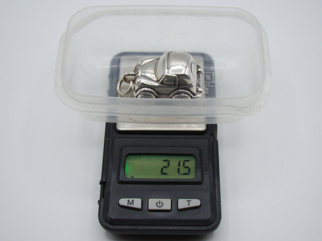 Silver miniature car on a scale displaying 21.5 grams