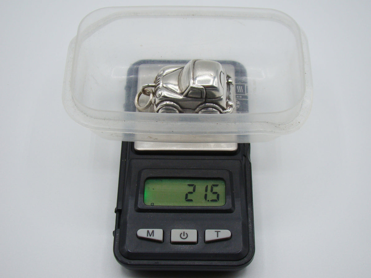 Silver miniature car on a scale displaying 21.5 grams