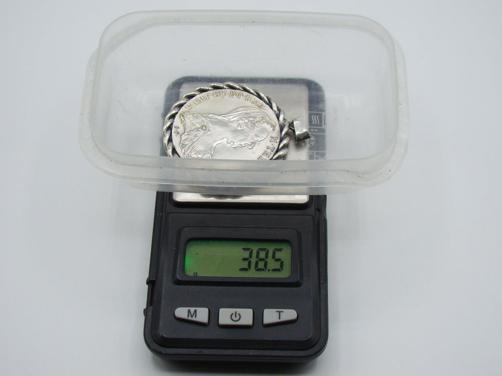 Mounted silver coin pendant on scale displaying total weight of 38.5 grams