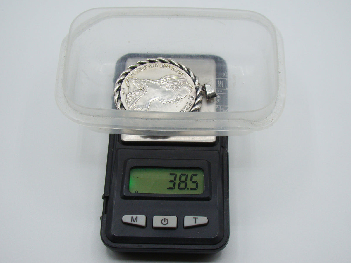 Mounted silver coin pendant on scale displaying total weight of 38.5 grams