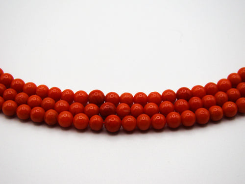 Close-up of the graduated red coral beads across the front of the three-strand necklace
